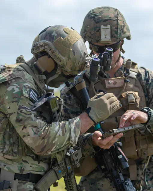 Two U.S. Marines heads-down over one tablet, checking what they see against the field around them.